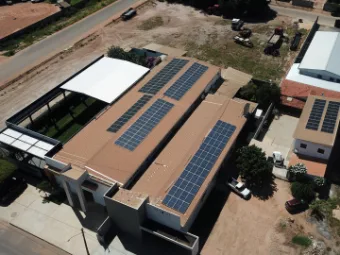 Comércio visto de cima, com fileiras de módulos solares cobrindo toda a extensão do telhado.