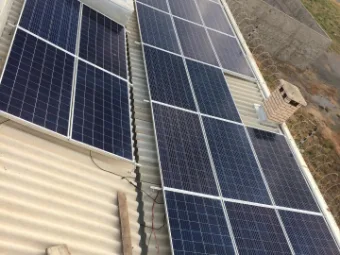 Técnico da Solar Led no telhado, ao lado dos módulos solares recém-instalados.