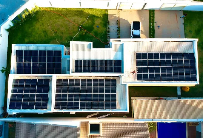 Residência vista de cima, com módulos solares distribuídos por três trechos do telhado.